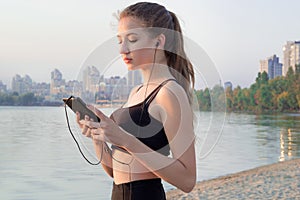 Young woman at coast listening to music on cell phone