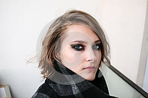 Young woman in coat with dark smoky eyes makeup