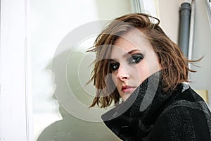 Young woman in coat with dark smoky eyes makeup