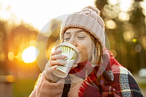 Young woman with coffee cup smiling outdoors during winter