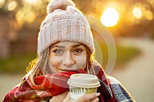 Young woman with coffee cup smiling outdoors during winter