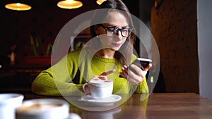 Young woman with coffee taking selfie photo with cellphone in cafe