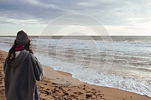 Young woman on cold autumn seashore posing at camera