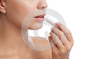 Young woman with cold sore applying lip balm against background, closeup