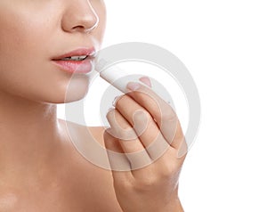 Young woman with cold sore applying lip balm against background, closeup