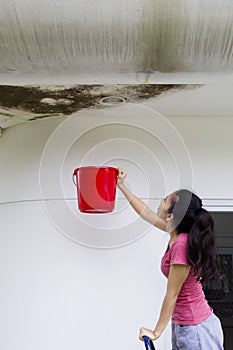 Young woman collecting rainwater with a bucket