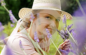 A young woman collects lavender Lavandula angustifolia , which smells beautiful and has a wonderful purple color. Summer time