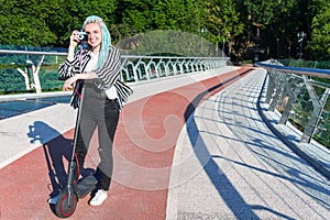 Young woman with colored dreadlocks  riding electric scooter