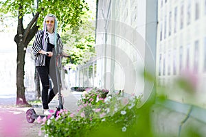 Young woman with colored dreadlocks  riding electric scooter