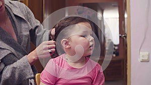 Young woman is combing girl`s hair