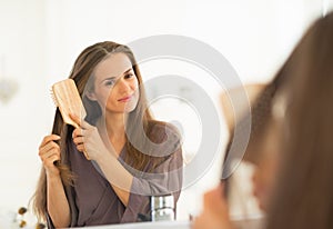 Young woman combing hair in bathroom