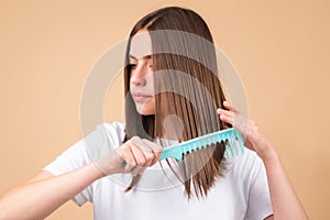 Young woman combing healthy and natural shiny hair, isolated on studio. Beauty hair care.