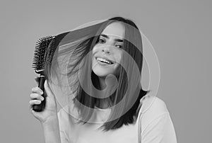 Young woman combing healthy and natural shiny hair, isolated on studio. Beauty hair care.