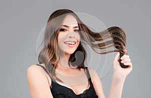 Young woman combing healthy and natural shiny hair, isolated on studio. Beauty hair care.