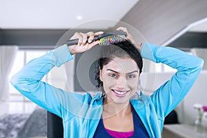 Young woman combing her hair in the bedroom