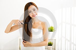 Young woman combing her hair in living room