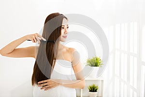 Young woman combing her hair in living room