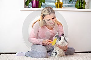 A young woman is combing her rabbit.Lovely pets.
