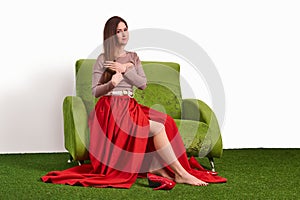 Young woman combing her while sitting on the couch in the studio and taking off her shoes while resting between shoots