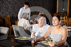 Young woman comforting upset female friend in restaurant