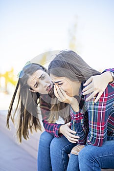 Young woman comforts a sad female friend