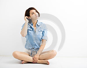 Young woman with confused gesture and sitting on floor