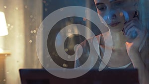 Young woman connecting with her laptop next to a window