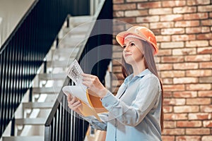 Young woman with construction plan indoors