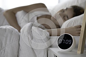 Young woman continues to sleep after turning off alarm clock in morning. focus on clock