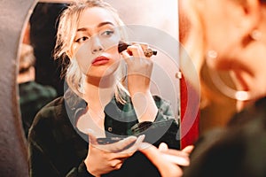 Young woman contouring her face applying make up with makeup brush