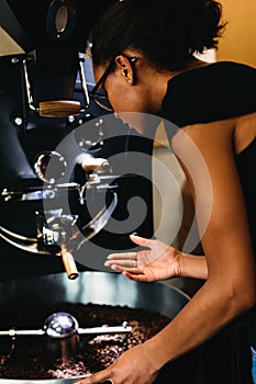 Young woman controlling process roasting coffee