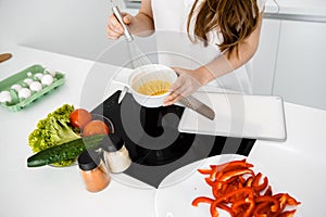 A young woman cook an omelette with vegetables.