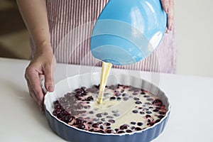 Young woman cooking in kitchen.Clafoutis cherry pie