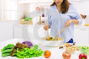 Young Woman Cooking in the kitchen. Healthy Food - Vegetable Salad. Diet. Dieting Concept. Healthy Lifestyle. Cooking At Home. photo