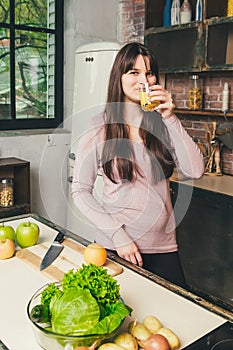 Young Woman Cooking in the kitchen at home. Healthy Food. Diet. Dieting Concept. Woman drinks orange juice