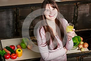 Young Woman Cooking in the kitchen at home. Healthy Food. Diet. Dieting Concept.Woman holding a glass with orange juice