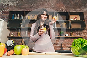 Young Woman Cooking in the kitchen at home. Healthy Food. Diet. Dieting Concept.Woman holding a glass with orange juice