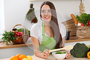 Young woman cooking in kitchen. Householding, tasty food and vegetarian in lifestyle concepts