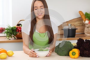 Young woman cooking in kitchen. Householding, tasty food and vegetarian in lifestyle concepts