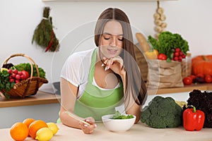 Young woman cooking in kitchen. Householding, tasty food and vegetarian in lifestyle concepts