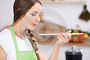 Giovane donna è un cucinando la cucina. casalinga è un degustazione secondo di legno cucchiaio 