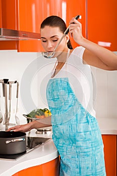 Young woman cooking in the kitchen, tasting soup