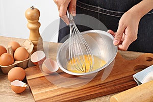 Young woman cooking omelet on table