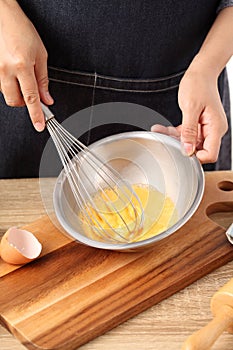 Young woman cooking omelet on table