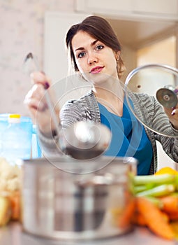 Young woman cooking soup with laddle