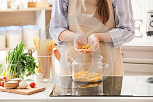 Young woman cooking tasty pasta in kitchen