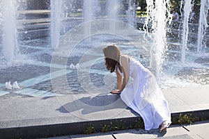 young woman cooling down next to city fountain during summer heat