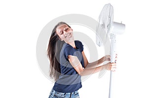 Young woman cooling herself under wind of cooler fan isolated on white background.