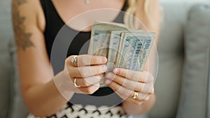 Young woman counting bangladesh 100 taka banknotes at home