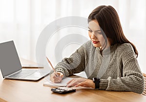 Young woman counting month spendings, working on budget